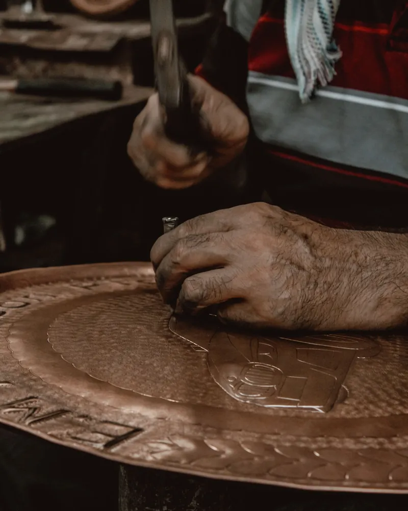Detalle de una chapa de cobre con el contorno trazado con cincel y el fondo trabajado con matizador